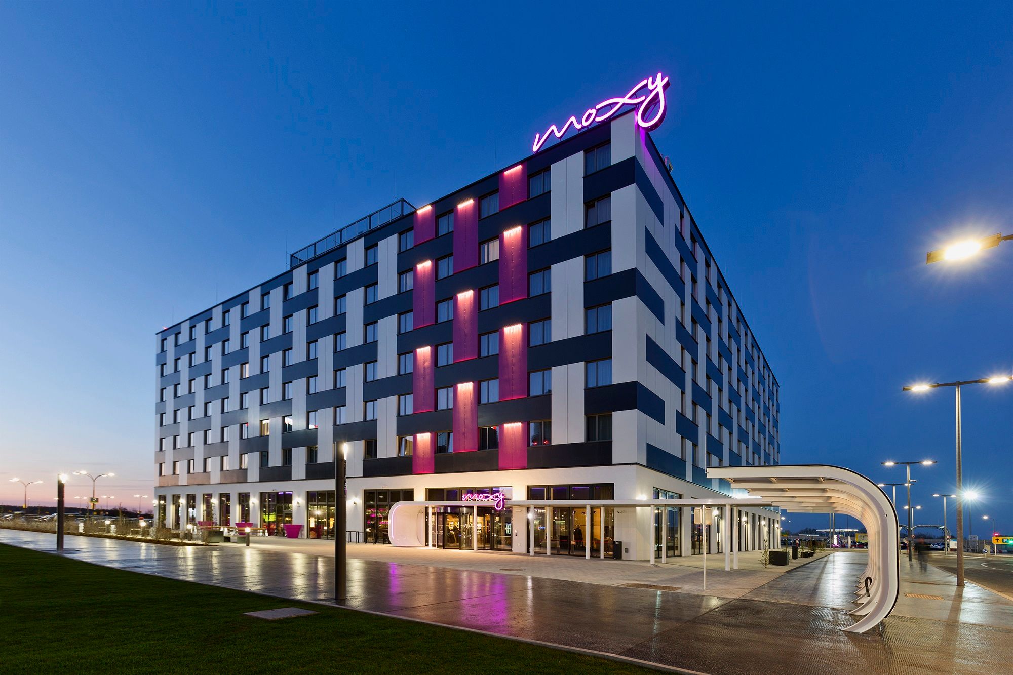 Exterior view of the Moxy Vienna Airport Hotel at dusk with illuminated lettering.