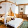 Cozy hotel room with four-poster bed, wooden furniture and carpets.