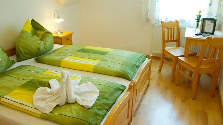 Guest room Hirschbüchler, © fotosemrad.at Cozy guest room with double bed, green bed linen and wooden furniture.