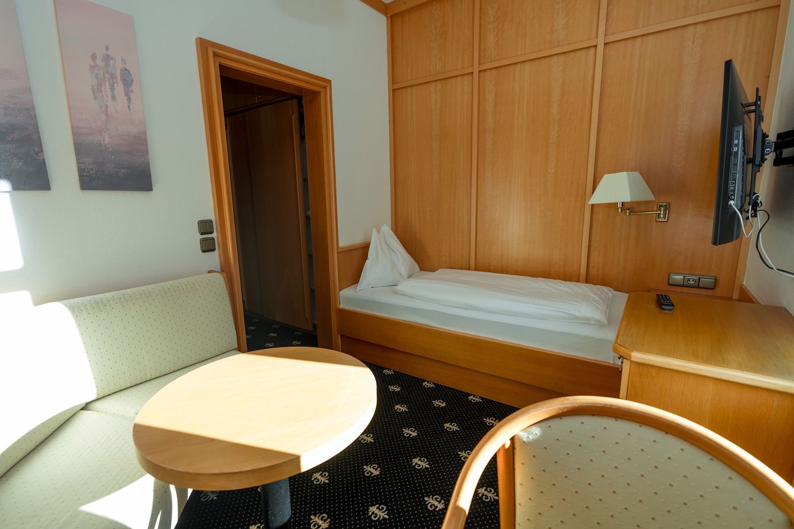 Single room with bed, sofa, table and TV.