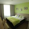 Modern guest room with green color scheme, double bed, desk and wall decorations.