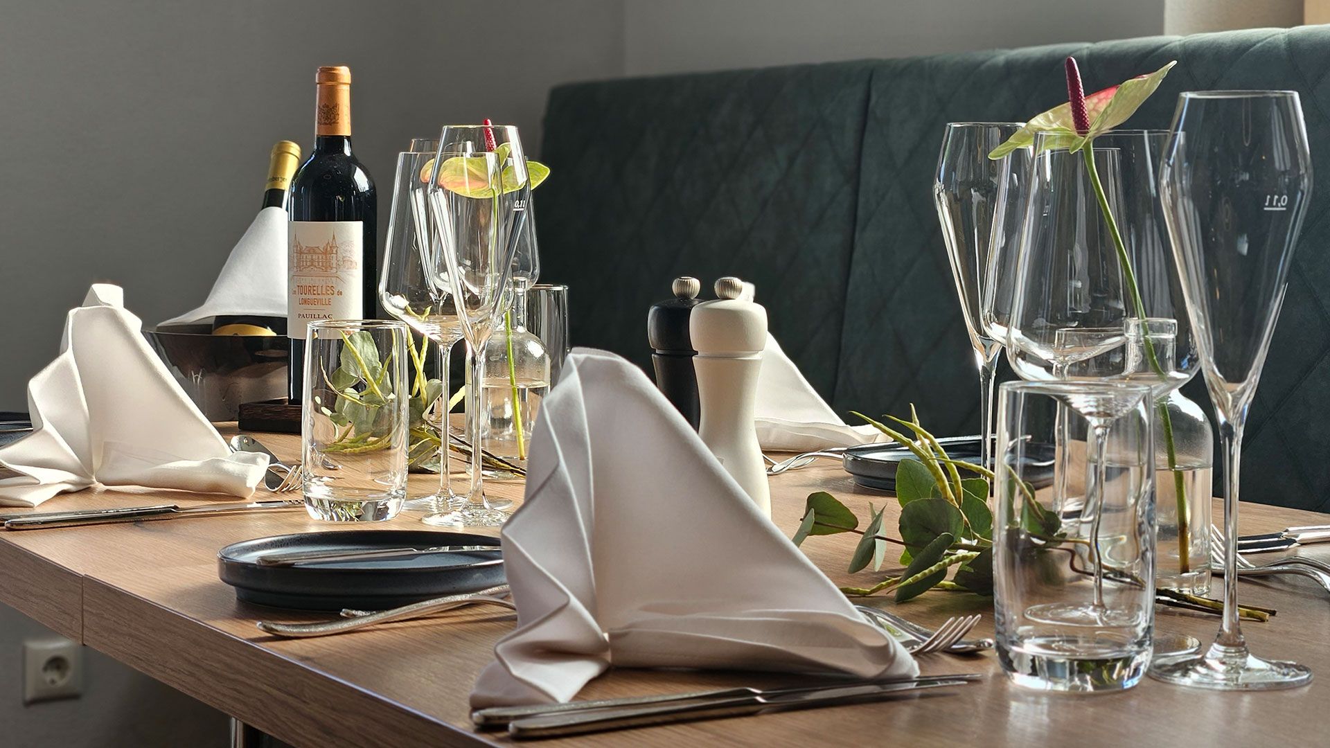 Elegant table setting with wine glasses, wine bottles and folded napkins.