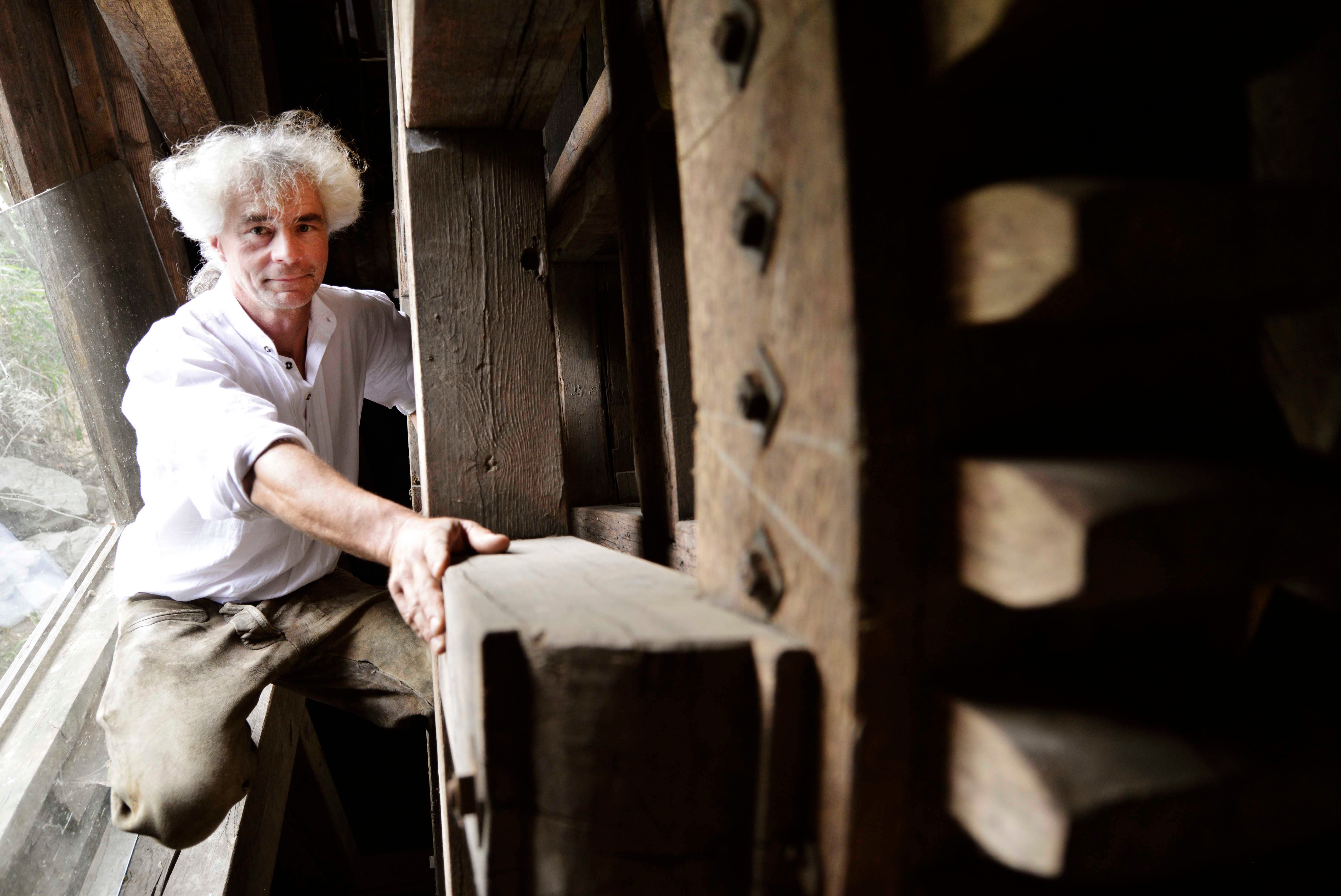 A man with white hair in an old wooden mill.