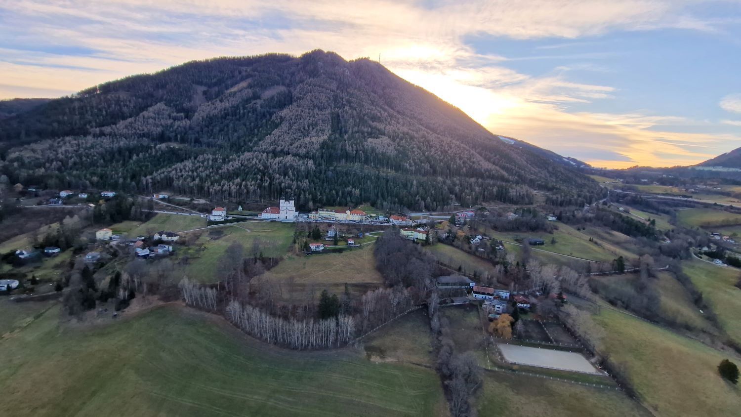 Landscape with church and mountains in the background at sunset.