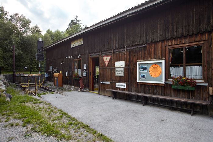 Wooden building with signs and flowers, part of an exhibition.