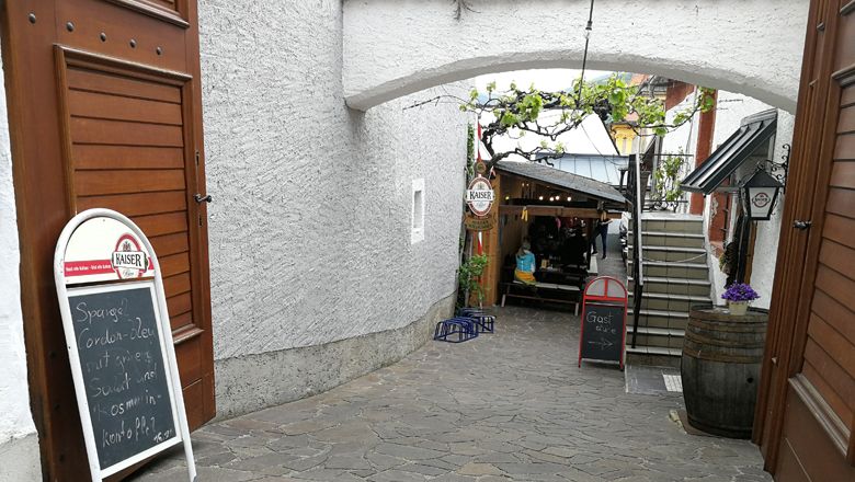 Entrance to a cozy courtyard with tables and plants.