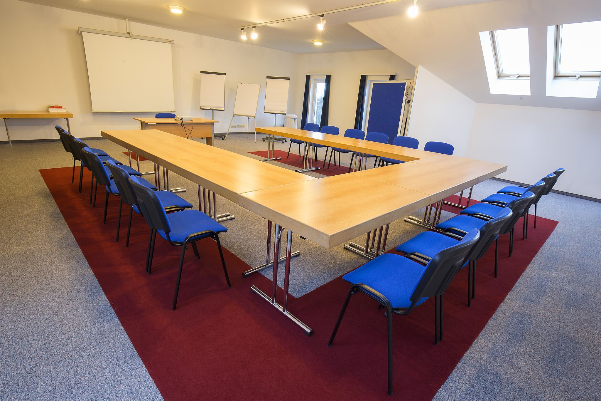 Conference room with U-shaped table and blue chairs.