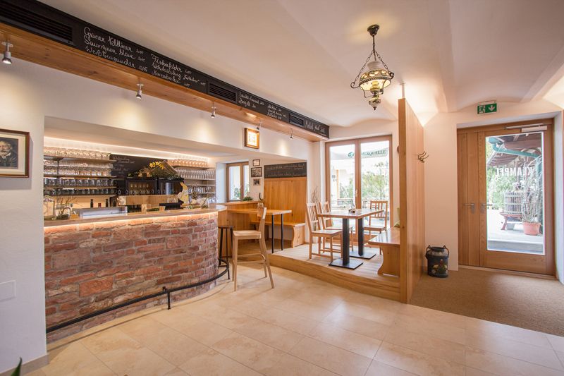 Interior view of a cozy wine bar with wooden furniture and brick counter.