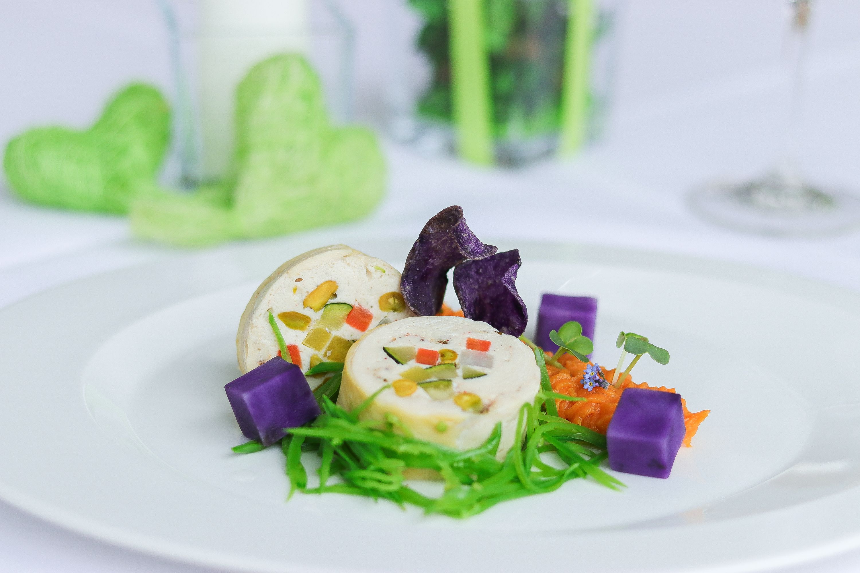 Gourmet dish with vegetables and purple potatoes on a white plate.