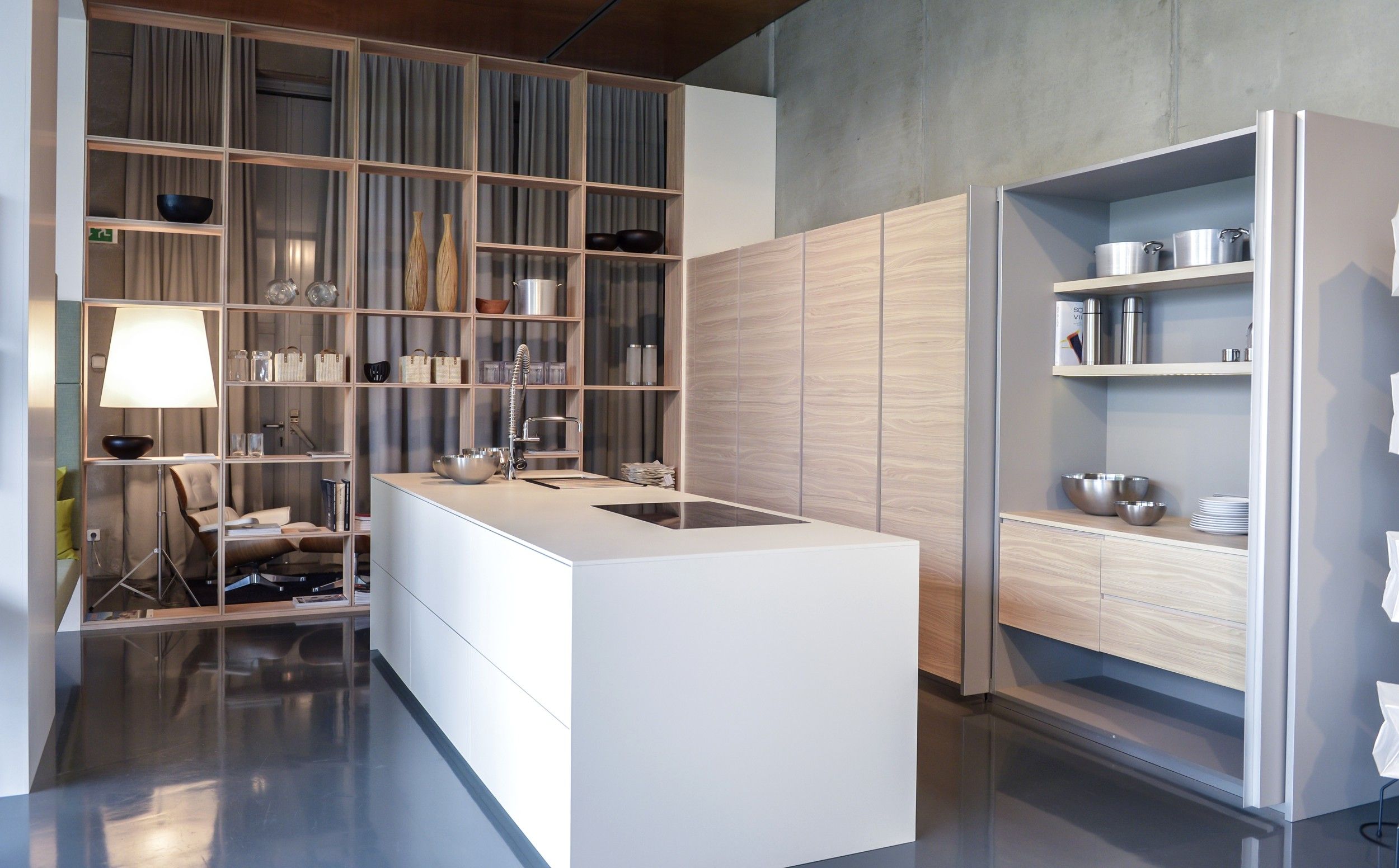 Modern kitchen with white island, shelves and wood paneling.