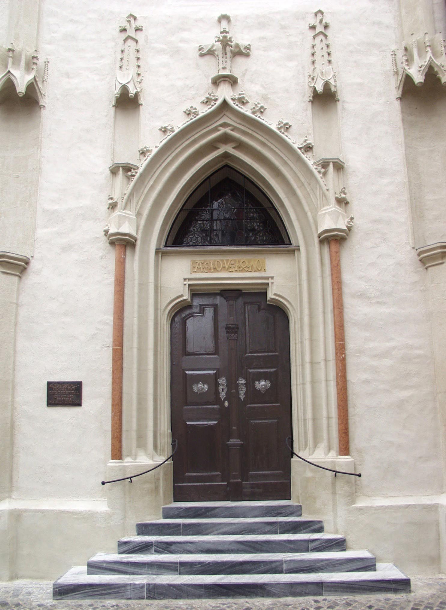 Entrance to the Bürgerspitalskirche with Gothic portal and wooden door.