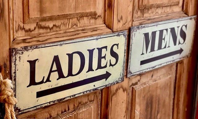 Signs for ladies' and men's toilets on wooden doors.