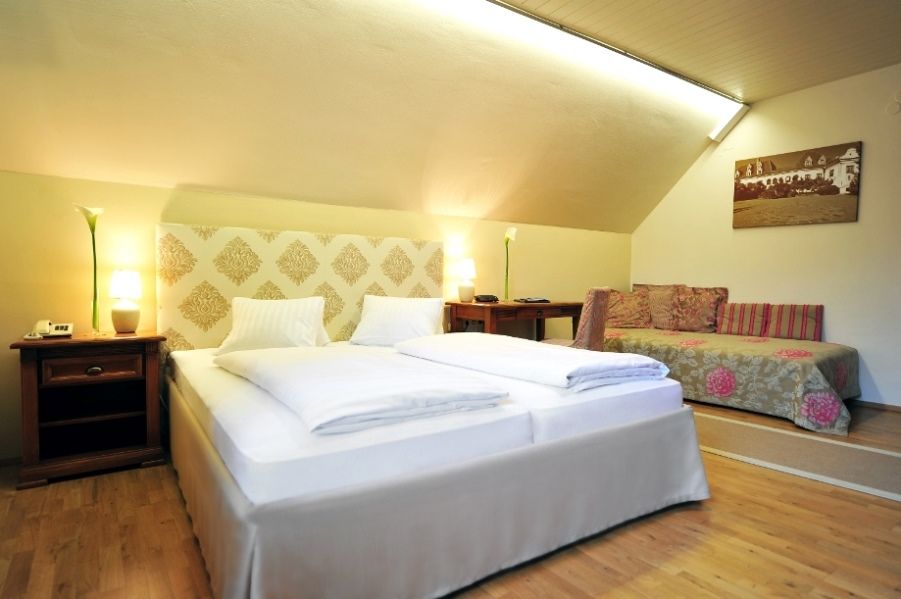 Hotel room with double bed, sofa and wooden furniture.