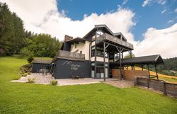 Ötscher Lodge in a green, wooded setting with a blue sky.