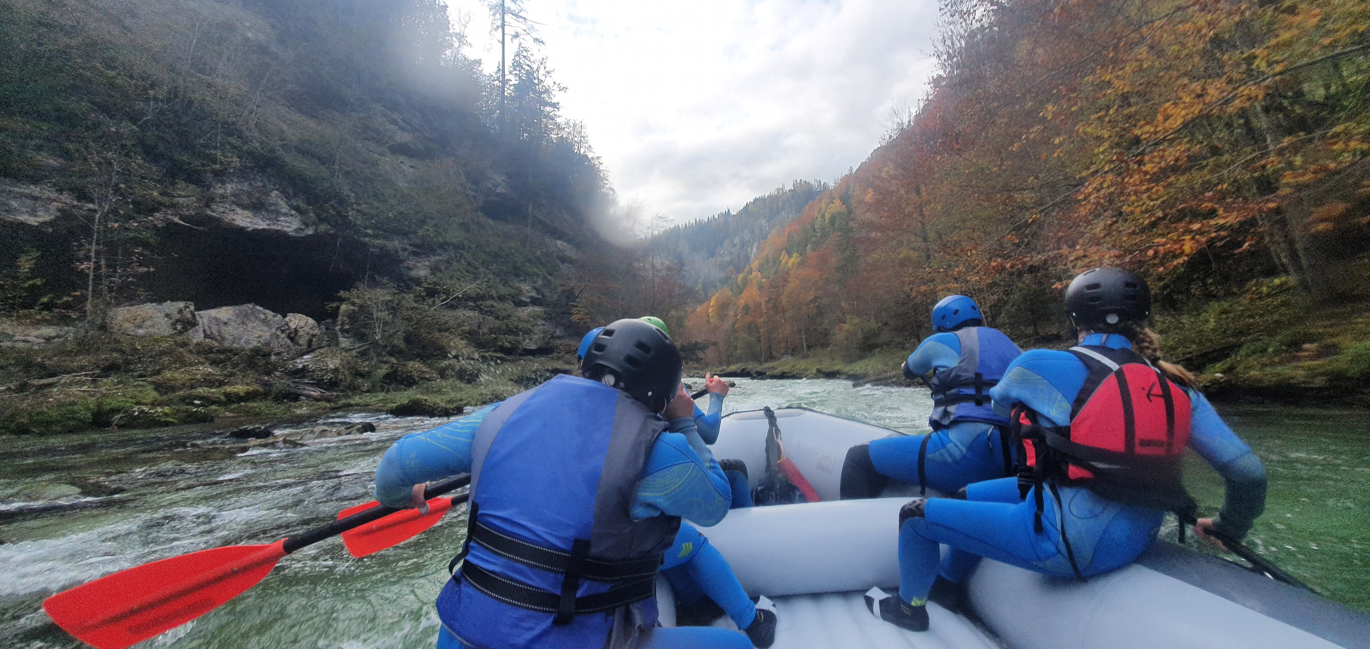 Group rafting on a river surrounded by autumnal trees.