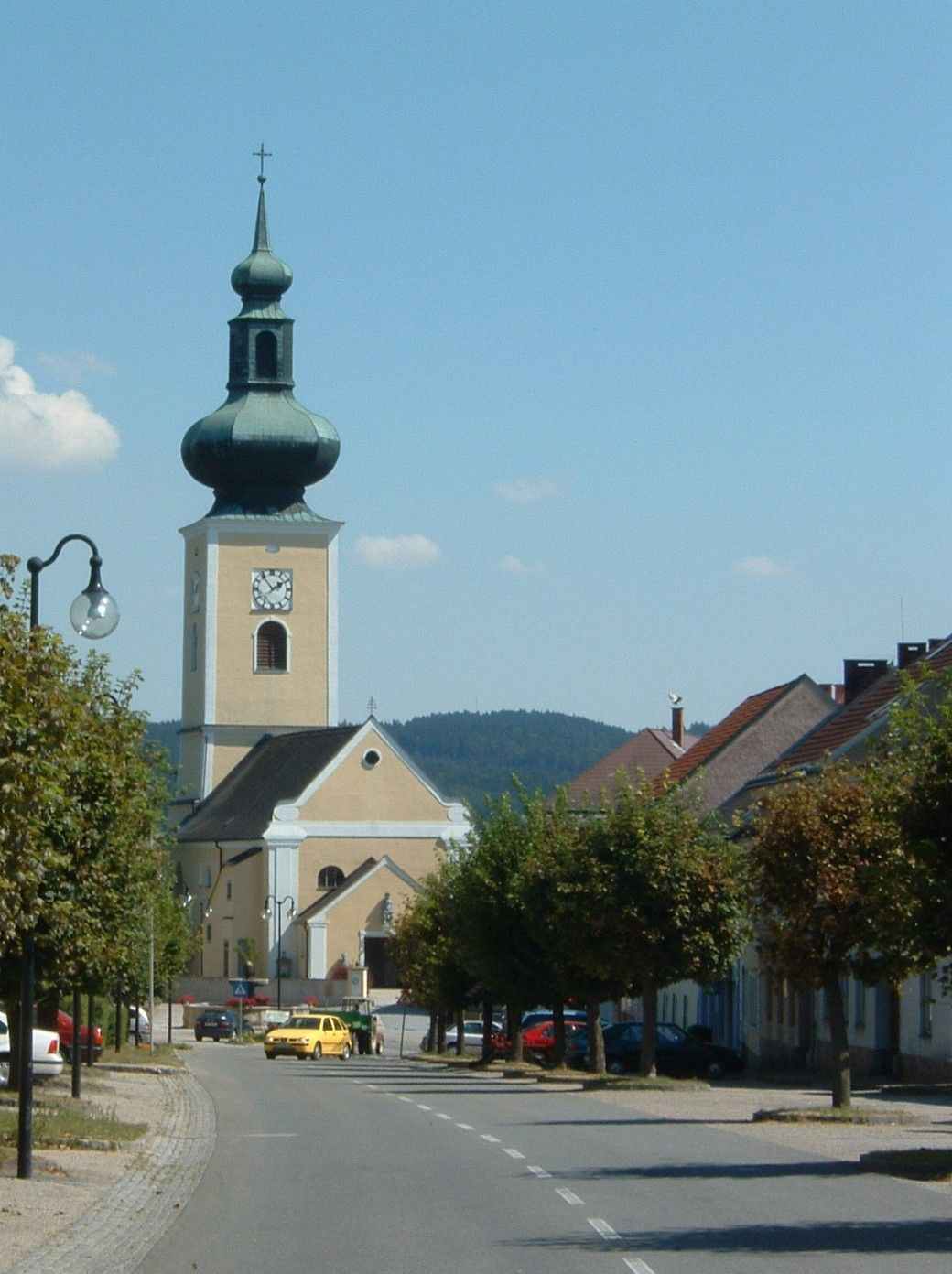 Church with onion dome in a small town, surrounded by trees and houses.