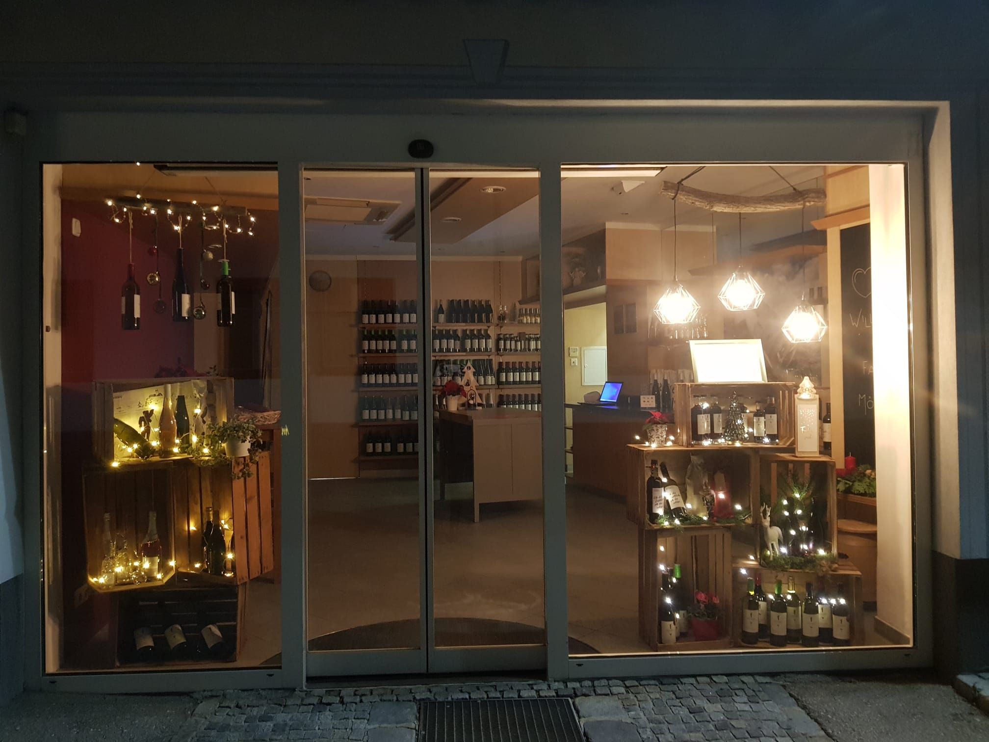 Wine store at night with illuminated shop window and wine bottles.