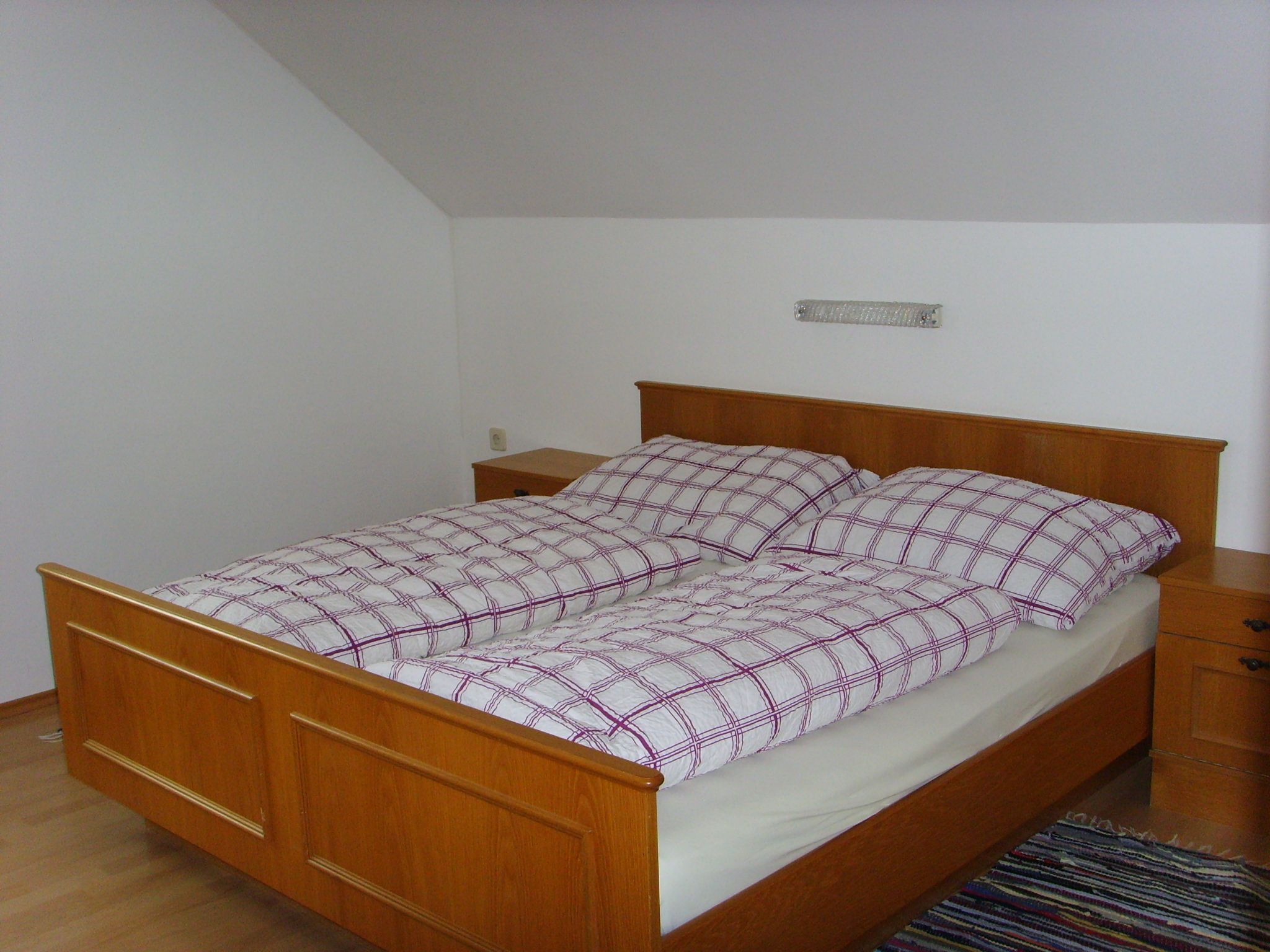 Bedroom with wooden bed and plaid bedding.