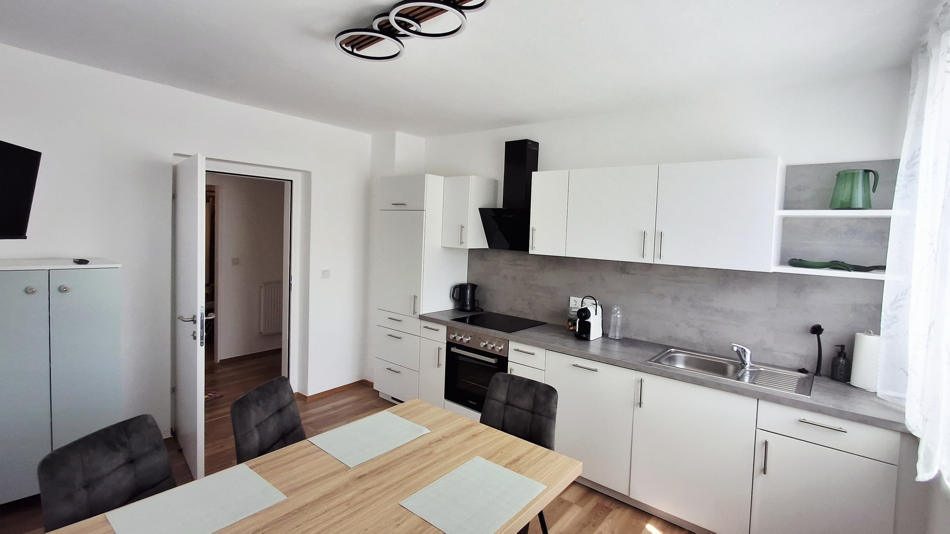 Modern kitchen with white cupboards, dining table and chairs in the Iwanestal guest house.