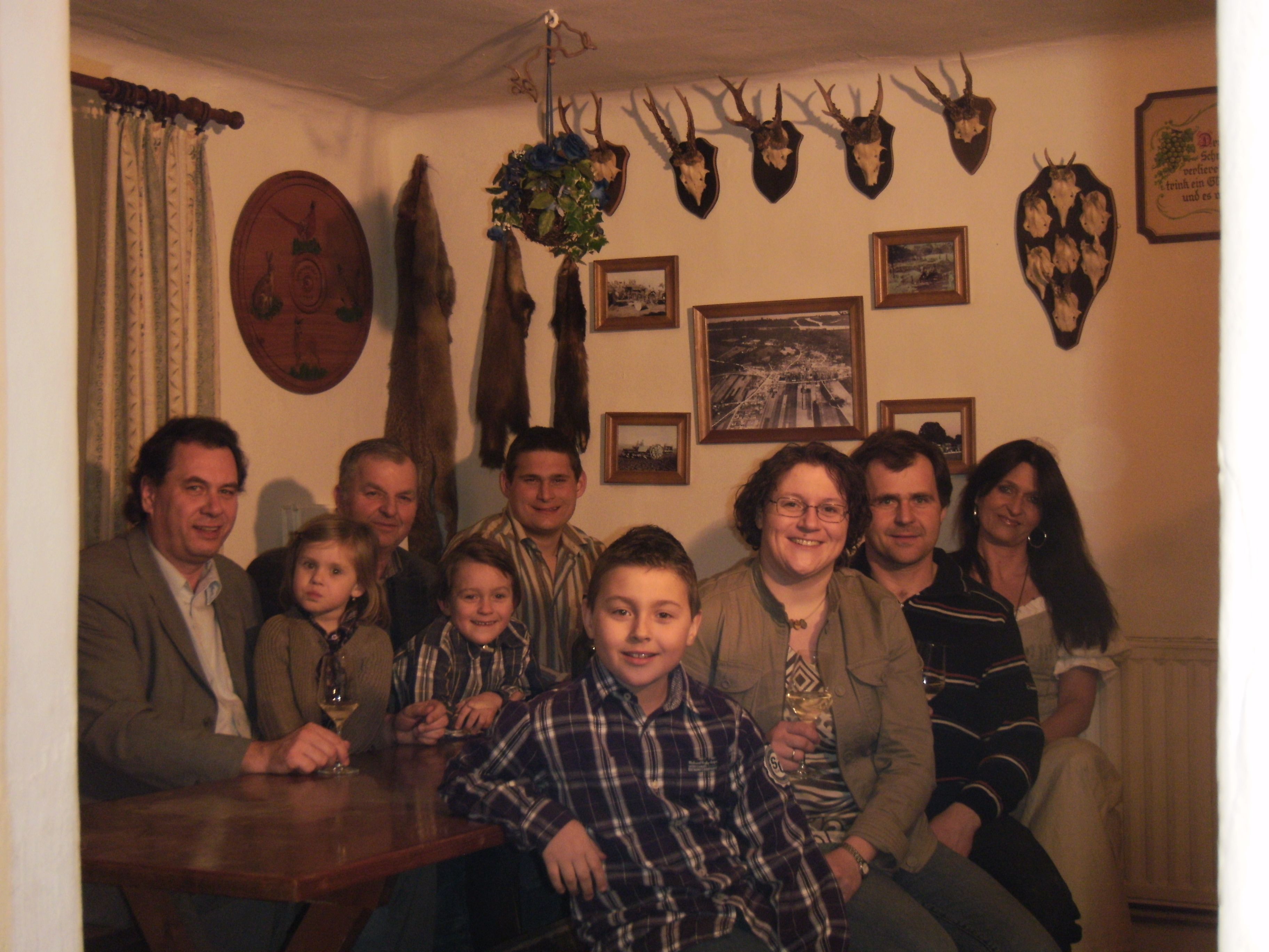 A group of people sit in a room with hunting trophies on the wall.