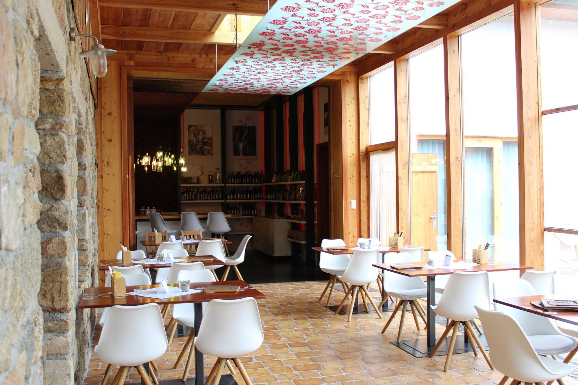 Interior view of a modern restaurant with white chairs and wooden tables.
