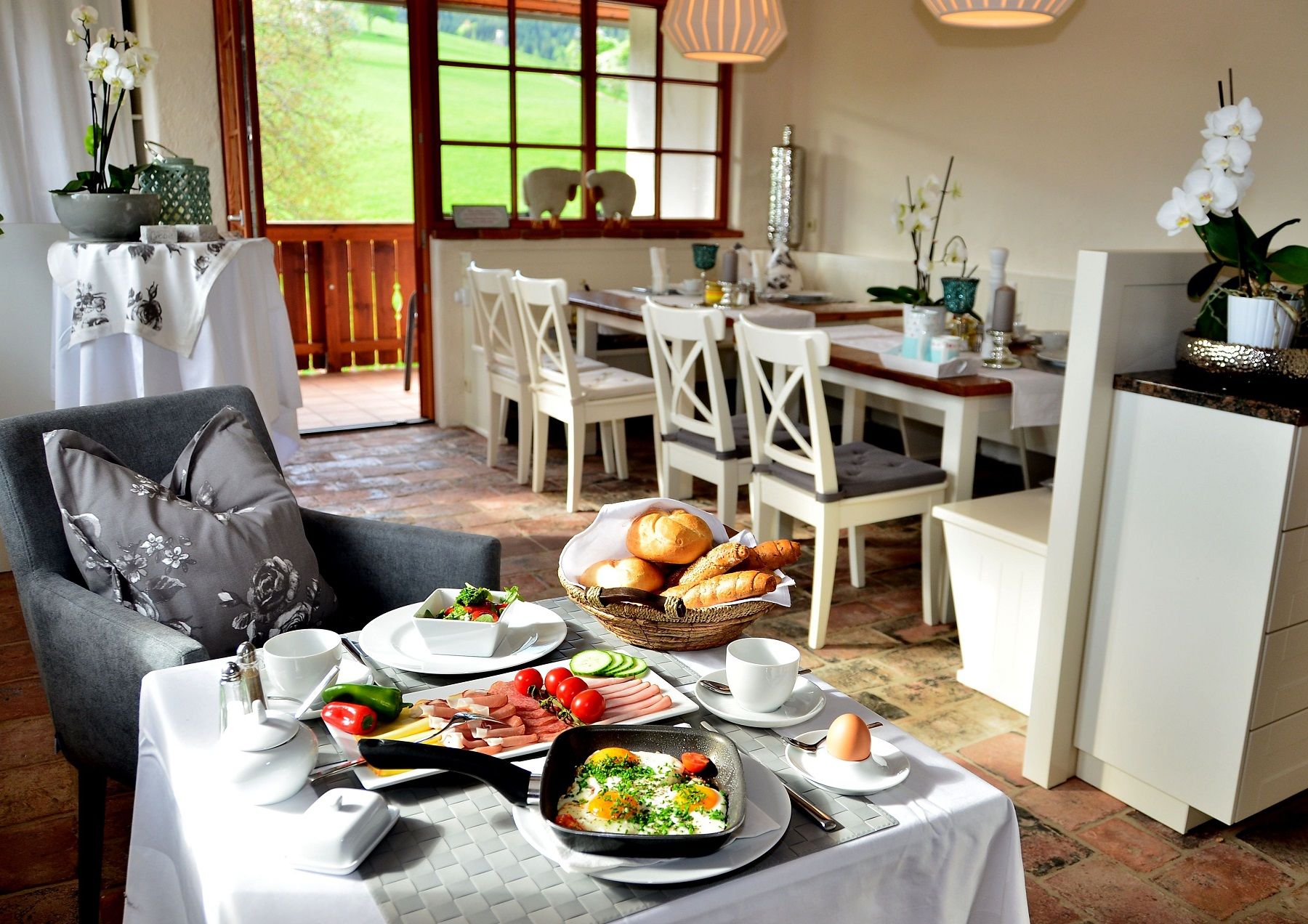 Breakfast table in a cozy dining room with a view of a green landscape.