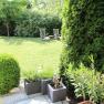 Garden with lawn, two sun loungers and plants in pots.