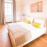 Bright bedroom with double bed, wooden floor and modern lamps.