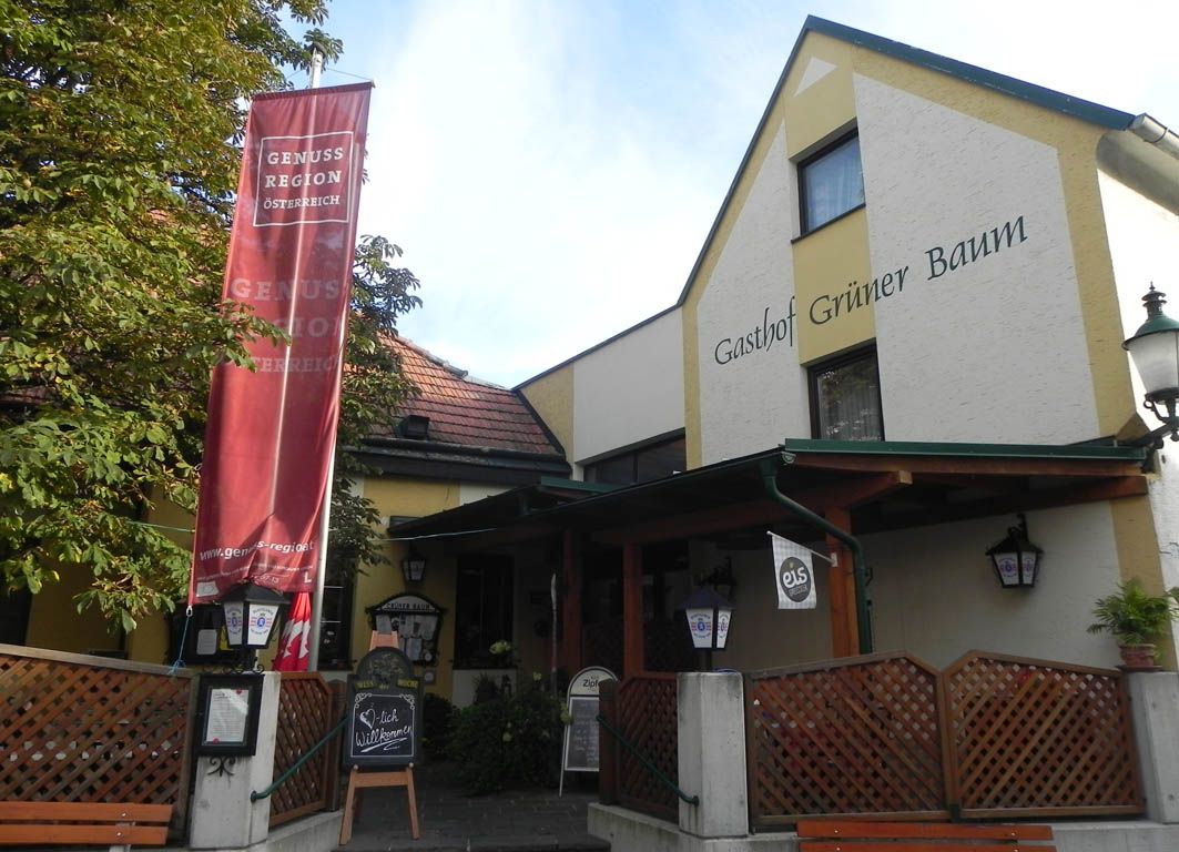 Entrance to the Grüner Baum inn with red banner and welcome sign.
