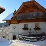 Traditional house with half-balcony and white fa&ccedil;ade, surrounded by snowy landscape.