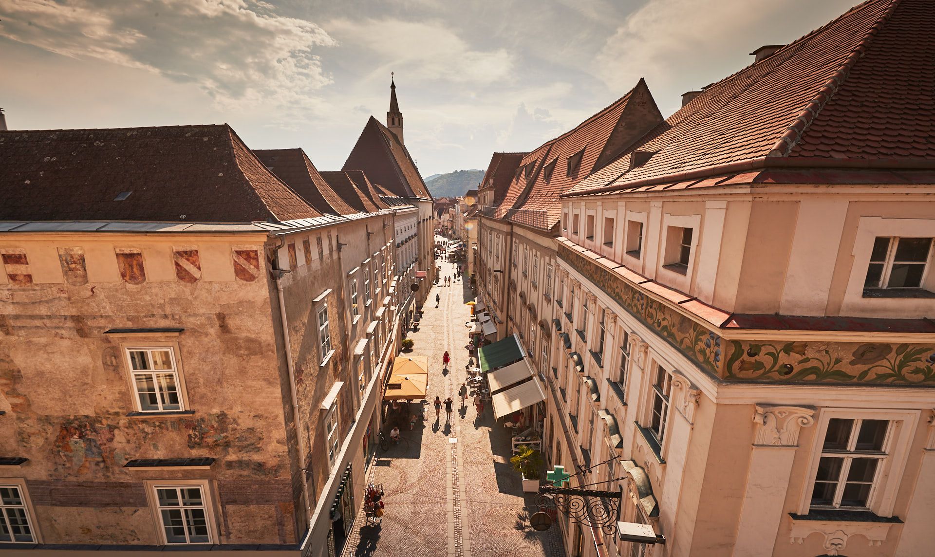View of a historic street in the old town of Krems with old buildings and people taking a walk.