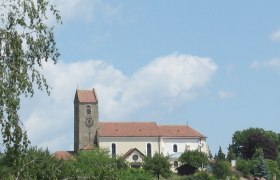 Church with tower and red roof in Hohenwarth, surrounded by trees and blue sky.