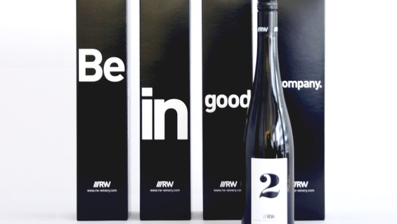 A bottle of wine in front of four black boxes with the inscription 'Be in good company'.