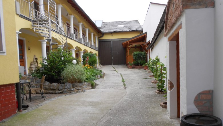 An inner courtyard with a yellow building, plants and a metal staircase.