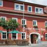 Red building with white window frames and green parasols in front of the entrance.