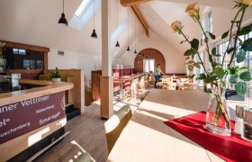 Interior view of a modern wine tavern with wooden furniture and large windows.