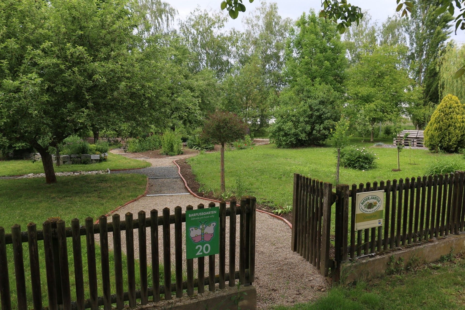 Entrance to a barefoot garden with gravel path and green surroundings.