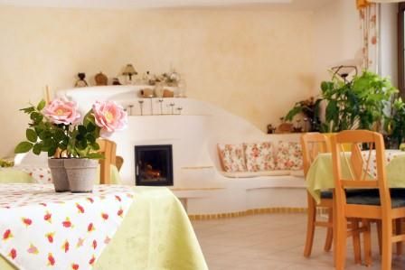 Cozy breakfast room with wooden furniture, plants and a small fireplace.