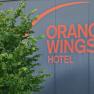Logo of the Orange Wings Hotel on a wall with plants in the foreground.