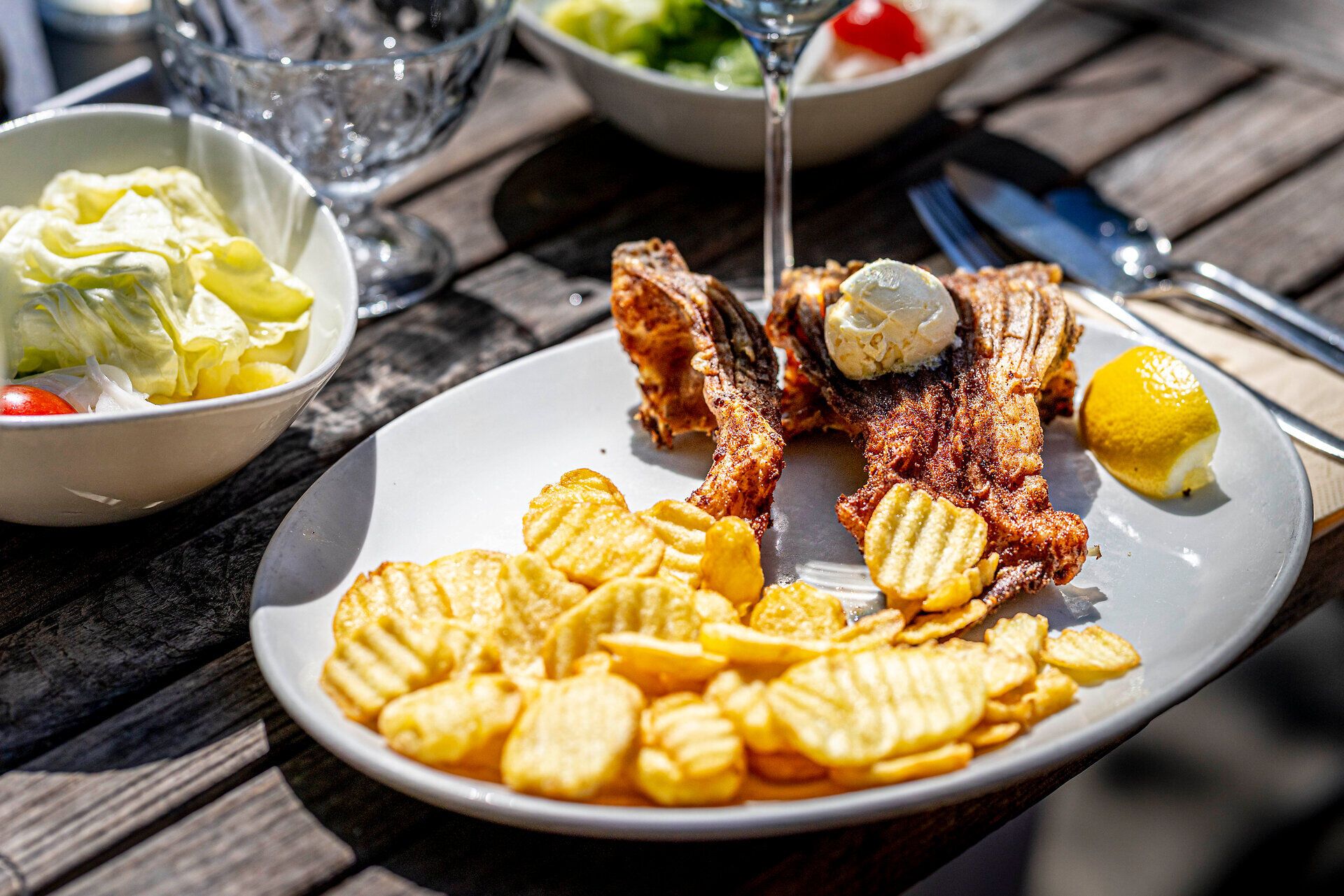 Fish dish and potato slices on a white plate. 
