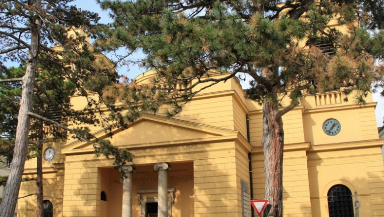 Exterior view of the Hinterbrühl parish with yellow façade and clock.