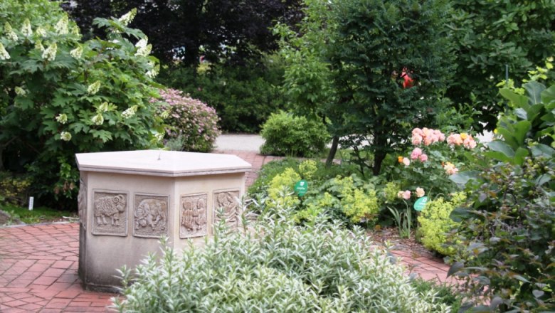A well-tended garden with a stone fountain and flowering plants.
