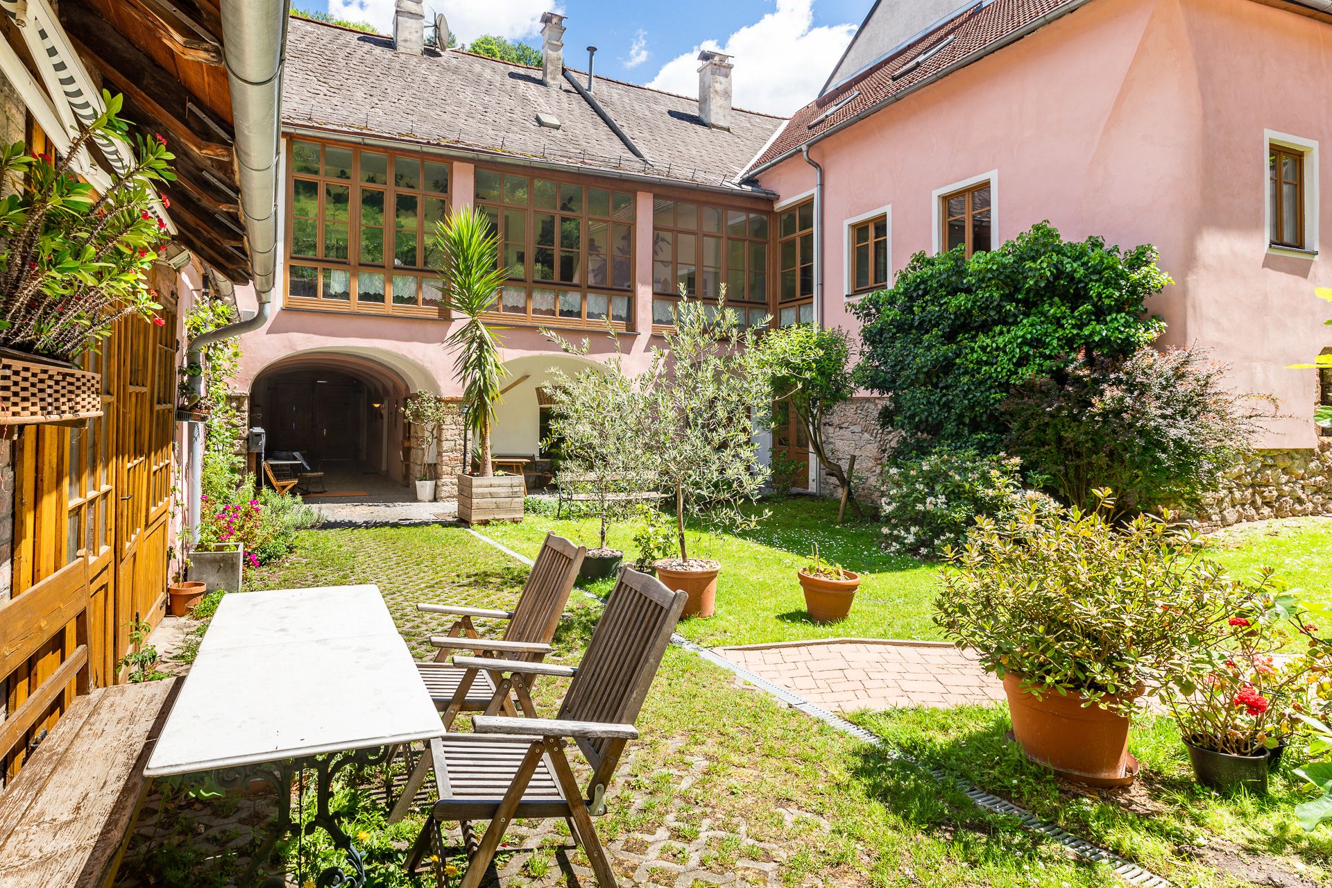 Inner courtyard with garden furniture, plants and pink building in the background.