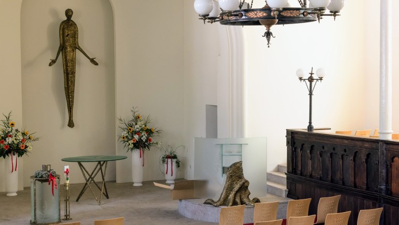 Interior of a church with modern decoration, flower arrangements and a statue.