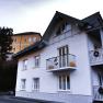 Two houses, one white with a balcony, the other yellow, with decoration.