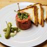 Beef tartare with capers, gherkins and toast on a plate.