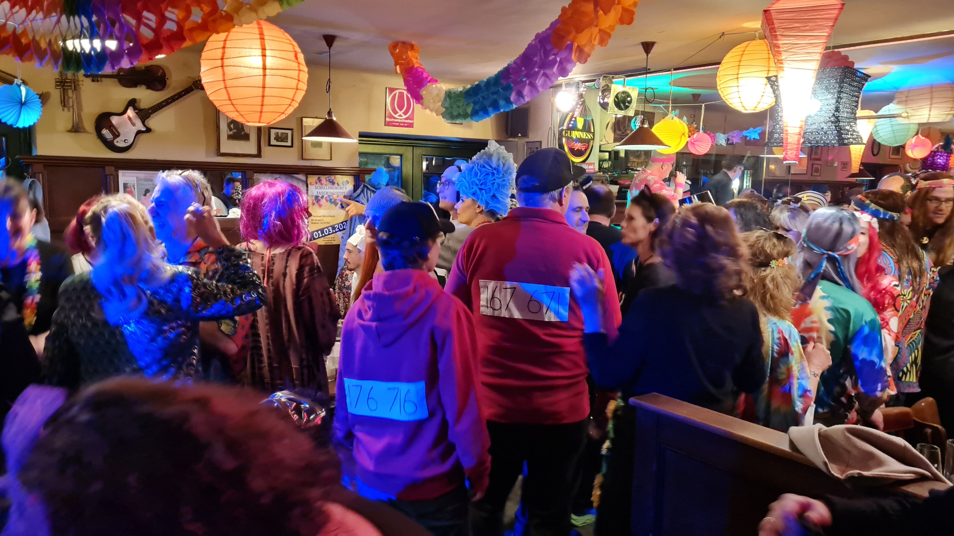 People in colorful costumes celebrate carnival in a decorated room.