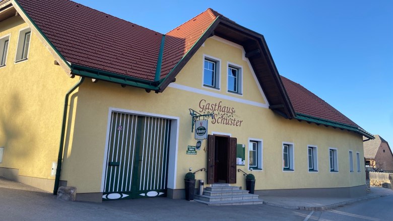 Yellow building with a red roof, labeled Gasthaus Schuster.