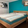 Bedroom with double bed, turquoise wall and flower picture.
