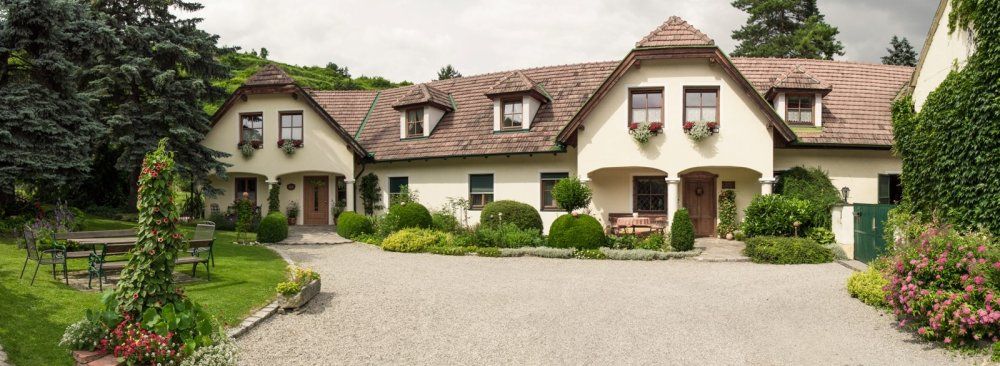 A traditional country house with a well-kept garden and gravel path.